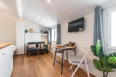 a living room with a table and a tv on the wall at FEEL HOME - COLLET in Nice