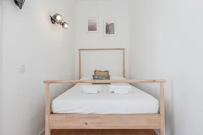 a bed in a white room with a wooden shelf at Lively district - Duplex Old Town in Nice