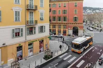 a bus driving down a city street with buildings at Joli 2 pièces au port de Nice in Nice