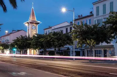 a clock tower on a city street at night at Orangers - Bord de mer - Studio cosy 4 personnes in Cagnes-sur-Mer
