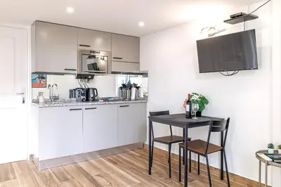 a kitchen with white cabinets and a black table and chairs at Studio Duplex Carré d'Or in Nice