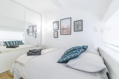 a white bedroom with a mirror on the wall at Studio Duplex Carré d'Or in Nice