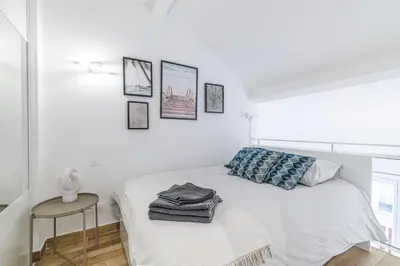 a white bedroom with a bed and a table at Studio Duplex Carré d'Or in Nice