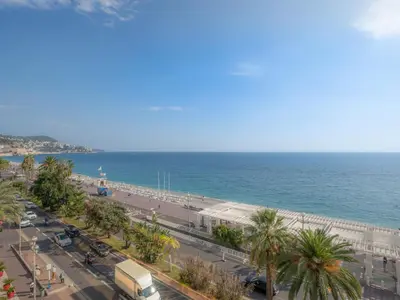 a view of a beach and the ocean with palm trees at Apartment Terrasses de la Baie des Anges by Interhome in Nice