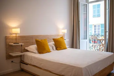 a bedroom with a bed with yellow pillows and a window at Magnifique 2P avec vue sur le port de Nice in Nice