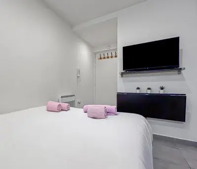 a bedroom with a white bed with pink pillows on it at Studio Centre Ville proche TRAM & Port, Wifi Gratuit in Nice