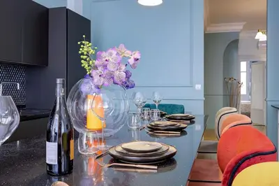 a dining room table with a vase of flowers and wine bottles at Luxury apartment in City Center of Nice in Nice