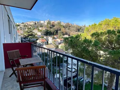 a balcony with two chairs and a view of a city at Bright appartment with view in Cagnes-sur-Mer
