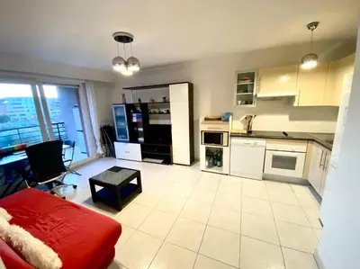 a kitchen with white appliances and a red couch at Nice Ouest St Isidore- 2P au calme in Nice