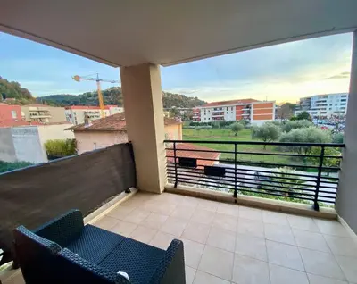 a balcony with two chairs and a view of a city at Nice Ouest St Isidore- 2P au calme in Nice