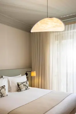 a room with a bed and a lamp and a pillow at Crisol Mozart in Nice