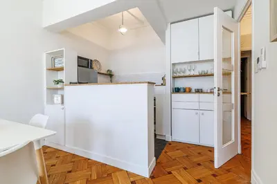a kitchen with white cabinets and wooden floors at Promenade des Anglais 2 Bdr Large Terrace in Nice