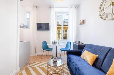 a living room with a blue couch and a table at Charming City Center Studio 104 in Nice