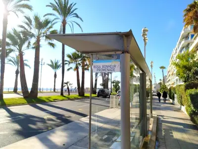 a bus stop on the side of a street with palm trees at Riviera Cocoon - Nice Center in Nice