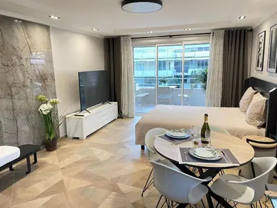 a living room with a bed and a table and a tv at STUDIO SUR LA PROMENADE DES ANGLAIS AVEC VUE MER ORIGINALE À 40 m DE LA PLAGE in Nice