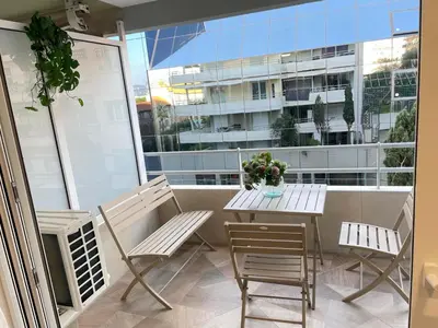 a balcony with a table and chairs and a building at STUDIO SUR LA PROMENADE DES ANGLAIS AVEC VUE MER ORIGINALE À 40 m DE LA PLAGE in Nice