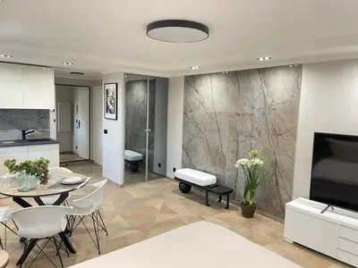 a kitchen and living room with a table and a television at STUDIO SUR LA PROMENADE DES ANGLAIS AVEC VUE MER ORIGINALE À 40 m DE LA PLAGE in Nice