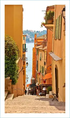 a narrow street with buildings and a body of water at Cosy Home in Villefranche-sur-Mer