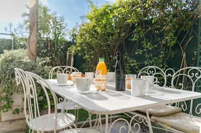 a white table with bottles of wine and chairs at Promenade des Anglais - 2 chambres - Jardin in Nice