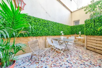 a patio with a table and chairs and plants at Promenade des Anglais - 2 chambres - Jardin in Nice