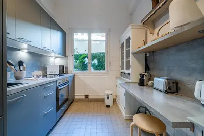 a large kitchen with blue cabinets and a window at Promenade des Anglais - 2 chambres - Jardin in Nice