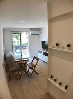 a living room with a table and chairs and a kitchen at Nice bas Cimiez- Coquet F1, climatisée, Parking in Nice