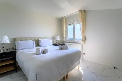 a bedroom with a large white bed with a window at VILLA BELLE VUE VI4394 By Riviera Holiday Homes in Villefranche-sur-Mer