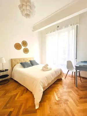 a white bedroom with a large bed and a desk at Cœur d'Azur Appartement in Nice