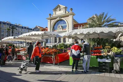 a group of people standing around a market with fruits and vegetables at Cœur d'Azur Appartement in Nice