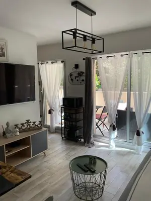 a living room with a table and a large window at Studio coin nuit terrasse parking Clim in Nice