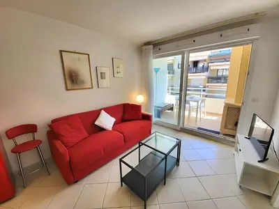 a living room with a red couch and a glass table at Appartement idéalement situé proche bord de mer in Beaulieu-sur-Mer