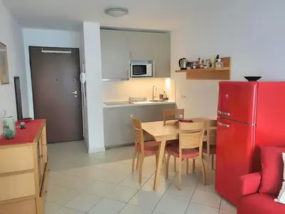a kitchen and dining room with a table and a red refrigerator at Appartement idéalement situé proche bord de mer in Beaulieu-sur-Mer