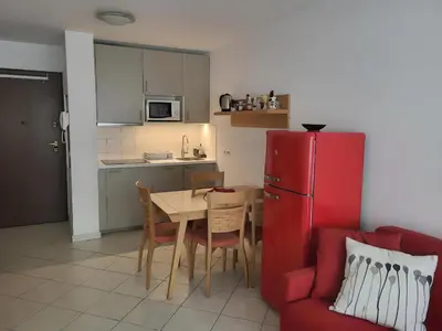 a kitchen with a table and a red refrigerator at Appartement idéalement situé proche bord de mer in Beaulieu-sur-Mer