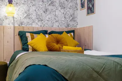 a bedroom with a bed with yellow and green pillows at Nice Renting - FODERE - Charm & Comfort 2P Heart of Nice - AC & WiFi in Nice