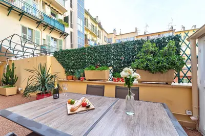a table with a vase of flowers and fruit on a balcony at Elegant apartment in Nice centre with grand terrace in Nice