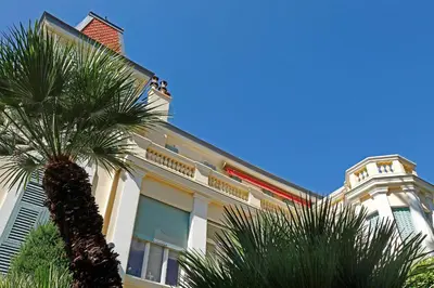 a building with a palm tree in front of it at PALMERAIE - Magnifique appartement d'époque avec Vue Mer 4 personnes avec terrasse Le Port Nice in Nice
