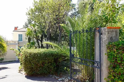a blue gate in a yard with bushes and trees at PALMERAIE - Magnifique appartement d'époque avec Vue Mer 4 personnes avec terrasse Le Port Nice in Nice