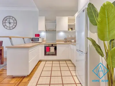 a kitchen with white cabinets and a clock on the wall at NEW Luxurious apartment - Jean Medecin in Nice