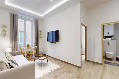 a living room with a couch and a tv on a wall at Suite Gold FSHH in Nice