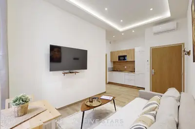 a living room with a couch and a tv on a wall at Suite Gold FSHH in Nice