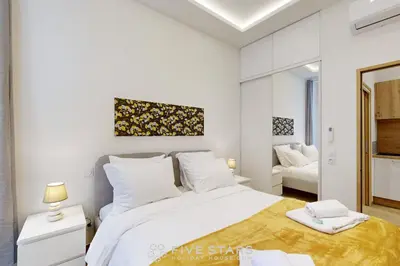 a white bedroom with a large bed and a mirror at Suite Gold FSHH in Nice