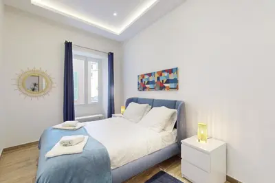 a white bedroom with a blue bed and a mirror at Suite Gold-Stars FSHH in Nice