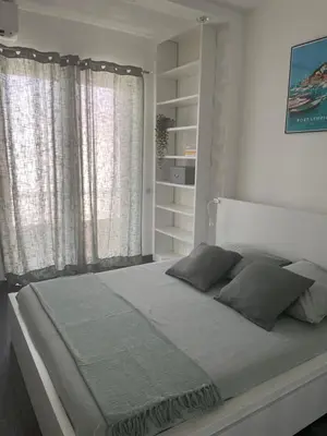 a white bedroom with a large bed with windows at Magnifique appartement avec vue sur mer in Nice
