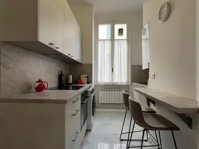 a kitchen with white cabinets and a counter and chairs at Maison Bianchi - 187 Promenade des Anglais - Sea view in Nice