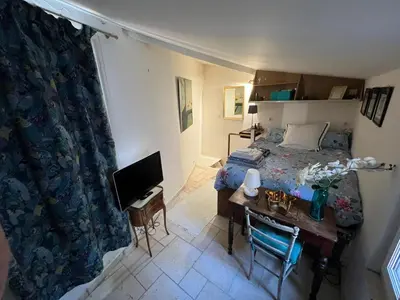 a bedroom with a bed and a desk with a television at Maison de 6 pièces au coeur du village d'Eze in Èze