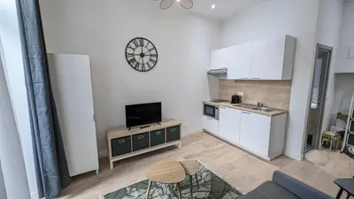 a kitchen with white cabinets and a tv in a room at COMBOUL in Nice