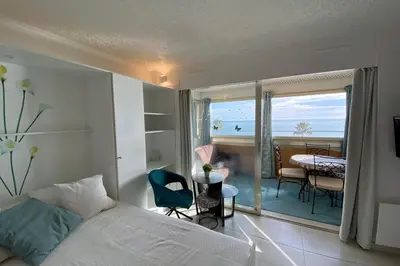 a bedroom with a bed and a balcony with a table at 06BH - Beautiful seafront studio in Saint-Laurent-du-Var