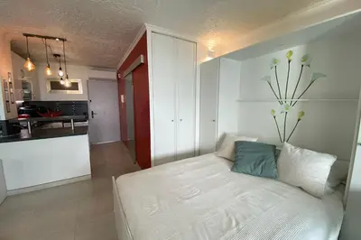 a bedroom with a white bed and a kitchen at 06BH - Beautiful seafront studio in Saint-Laurent-du-Var