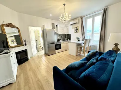 a living room with a blue couch and a kitchen at Lumineux appartement deux pièces in Nice