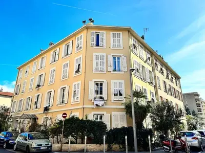 a yellow building with cars parked in front of it at Lumineux appartement deux pièces in Nice